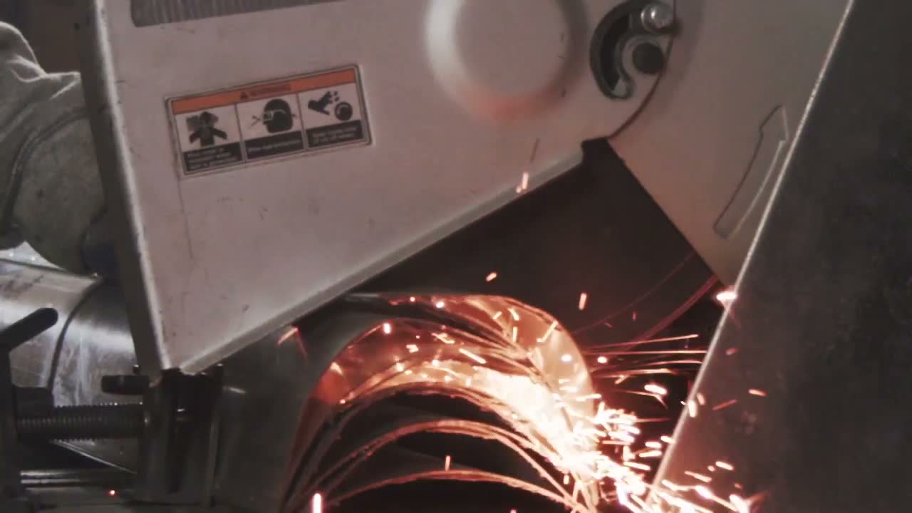 Orange sparks spraying off a metal cut-off saw in a dark workshop